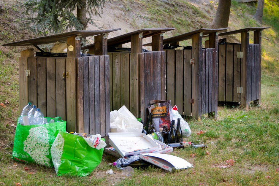 An expansive view of a large landfill or waste disposal site filled with a dense layer of mixed rubbish. The material includes various types of waste such as plastic bottles, paper, cardboard, and per